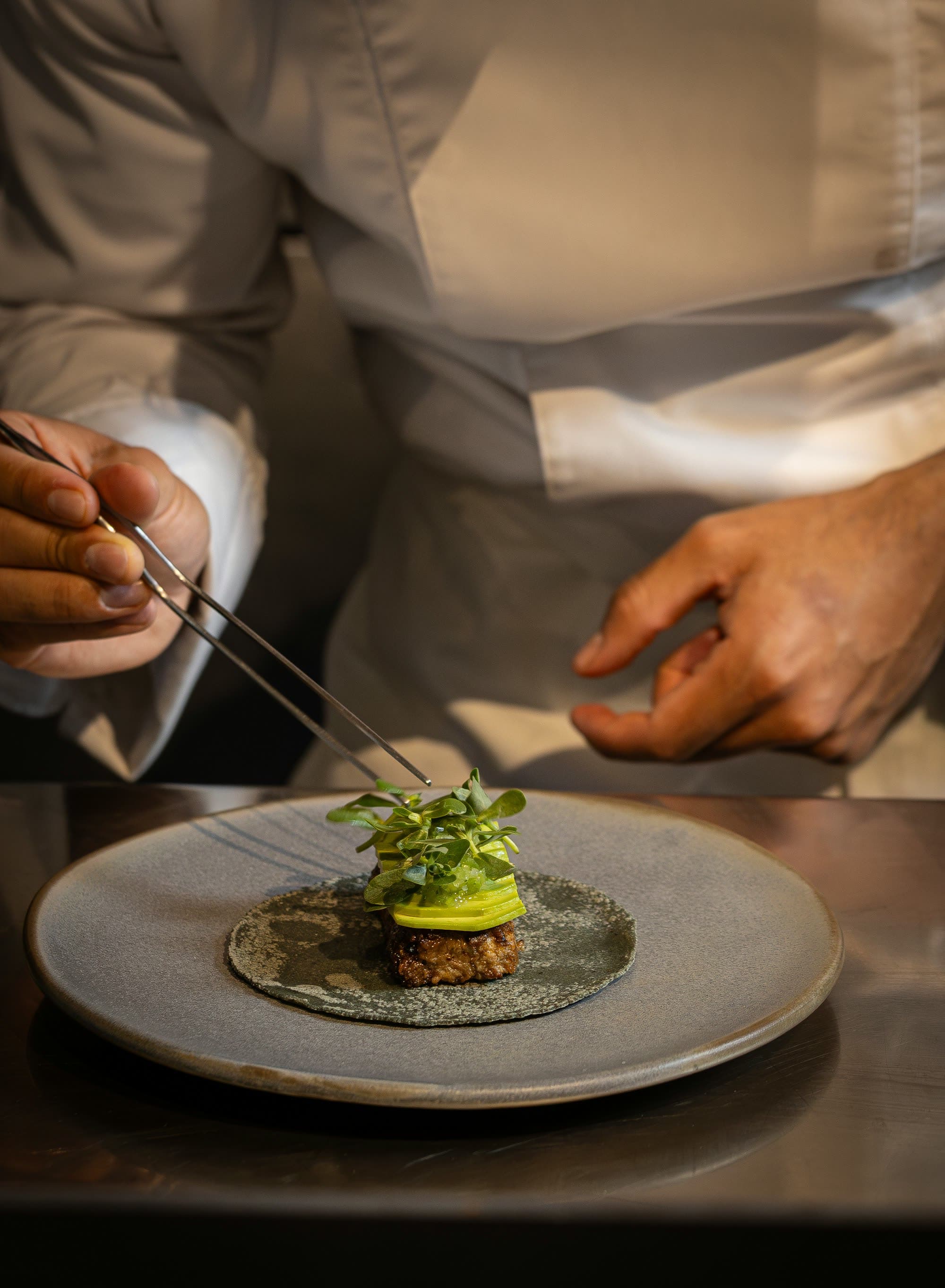 Les mains d'un chef finalisant le dressage d'une assiette