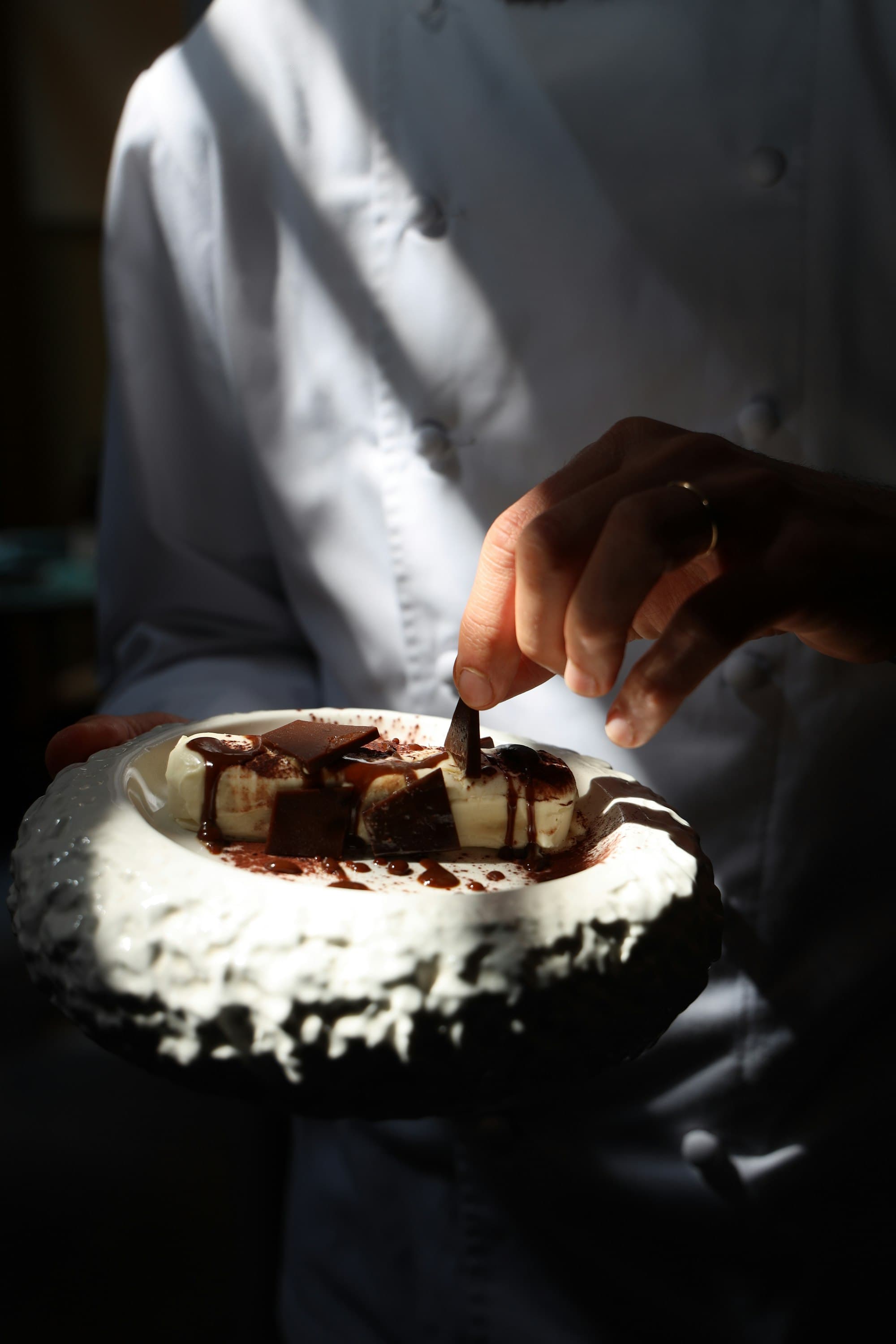 Un dessert au chocolat garni de copeaux, dressé à la main